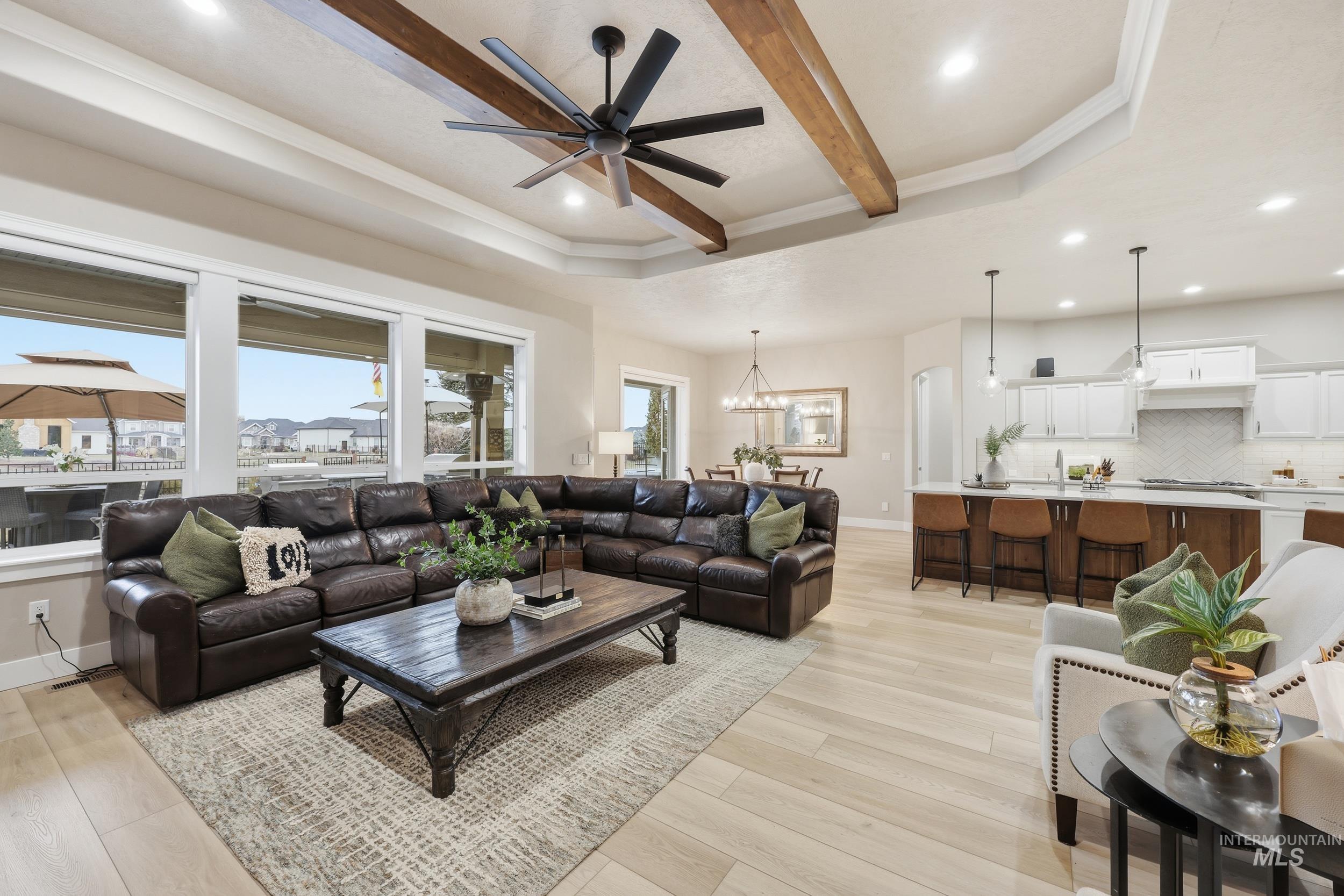 Living room with recessed lighting, light wood-style flooring, a chandelier, a ceiling fan, and beam ceiling