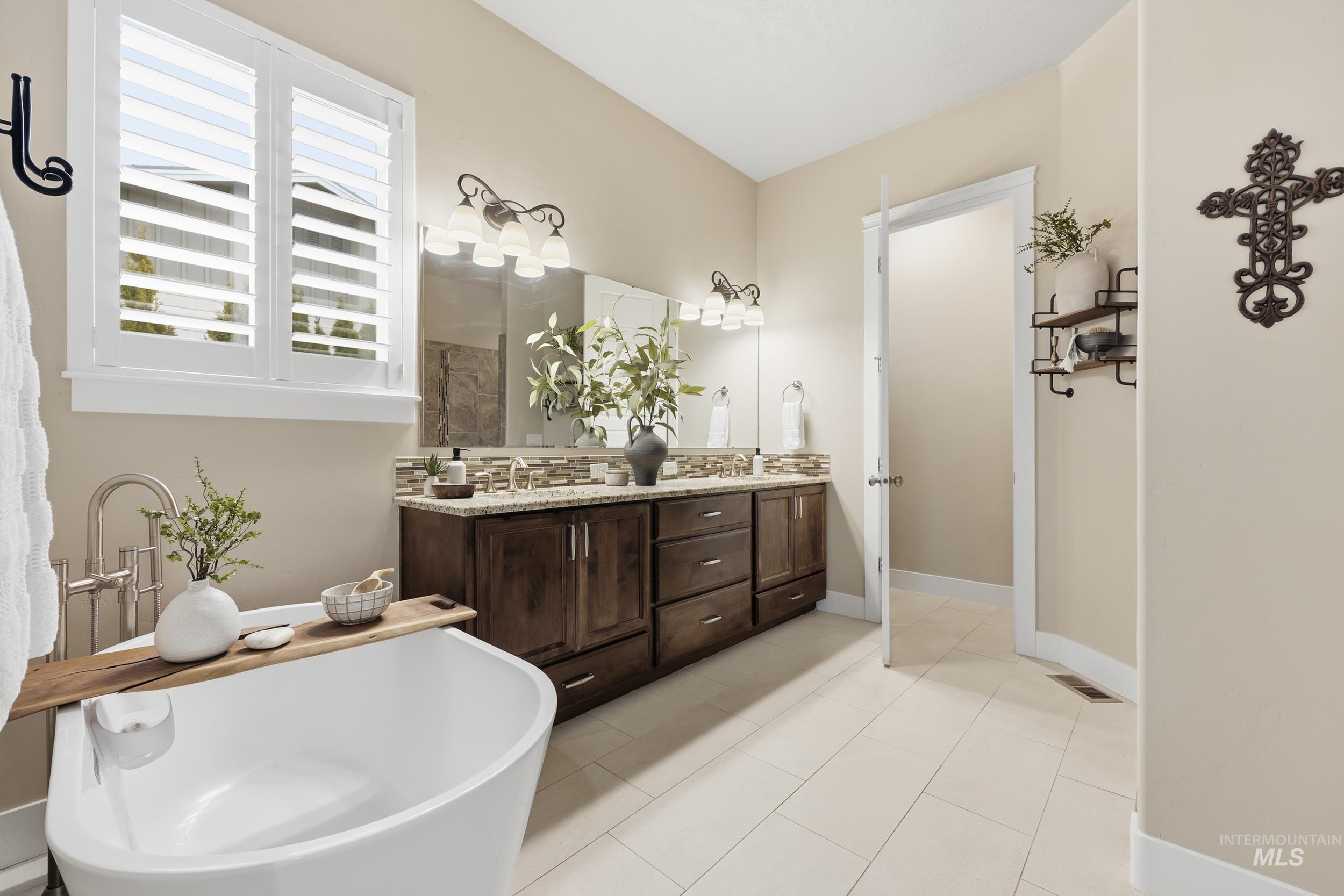 Bathroom with double vanity, light tile patterned floors, and a soaking tub