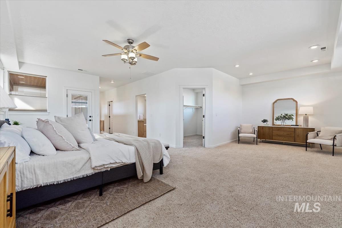 Carpeted bedroom featuring recessed lighting, a spacious closet, ceiling fan, and ensuite bathroom