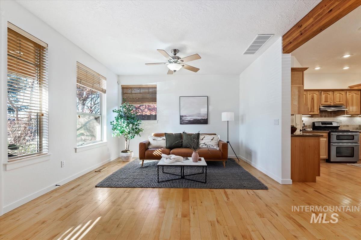 Living room with light wood-style flooring, ceiling fan, and a textured ceiling
