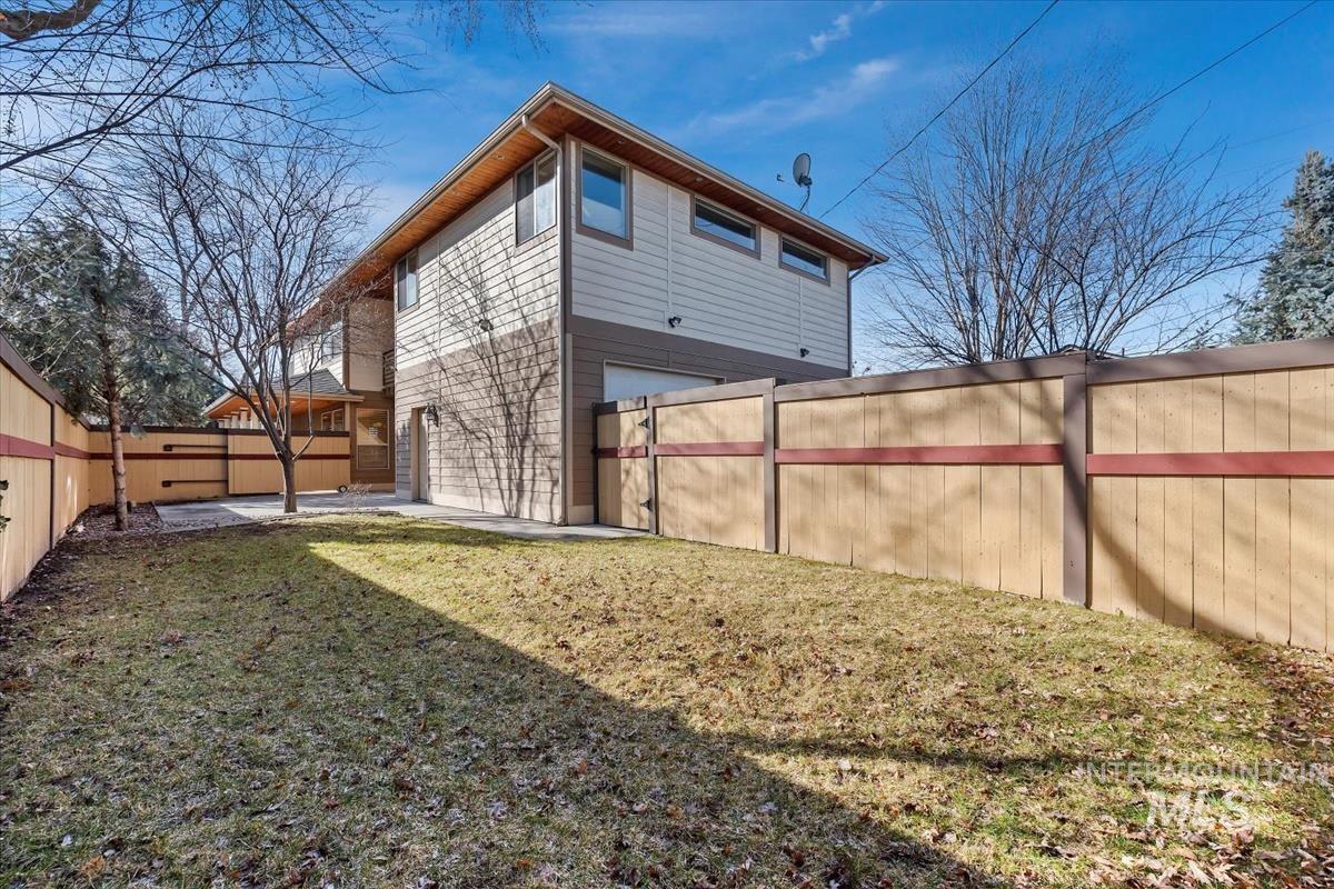 Rear view of property featuring a fenced backyard, a garage, and a patio