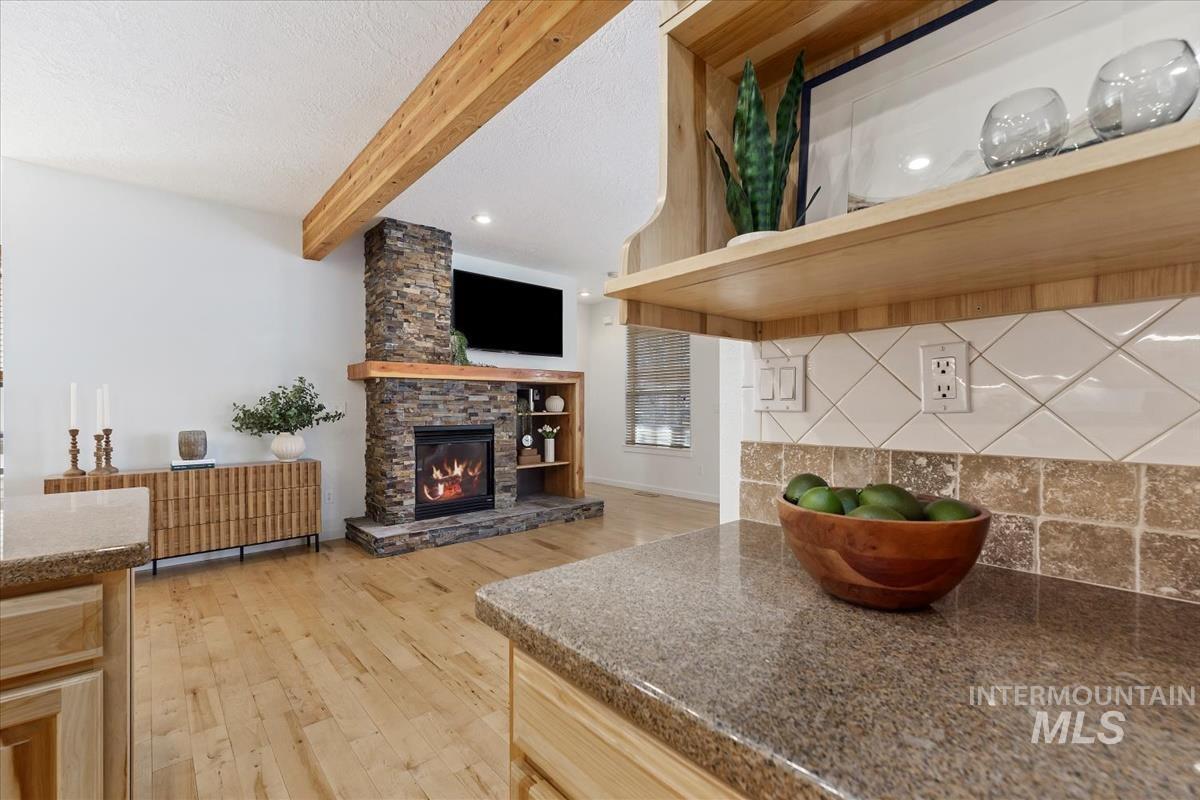 Living room featuring a fireplace, light wood-type flooring, beam ceiling, recessed lighting, and a textured ceiling