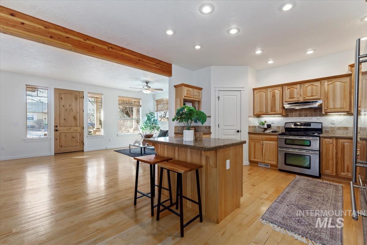 Kitchen featuring light wood-style floors, stainless steel appliances, tasteful backsplash, a kitchen island, and a kitchen breakfast bar