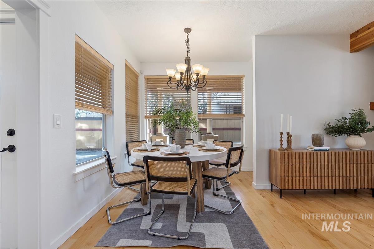 Dining area with healthy amount of natural light, wood finished floors, and a chandelier