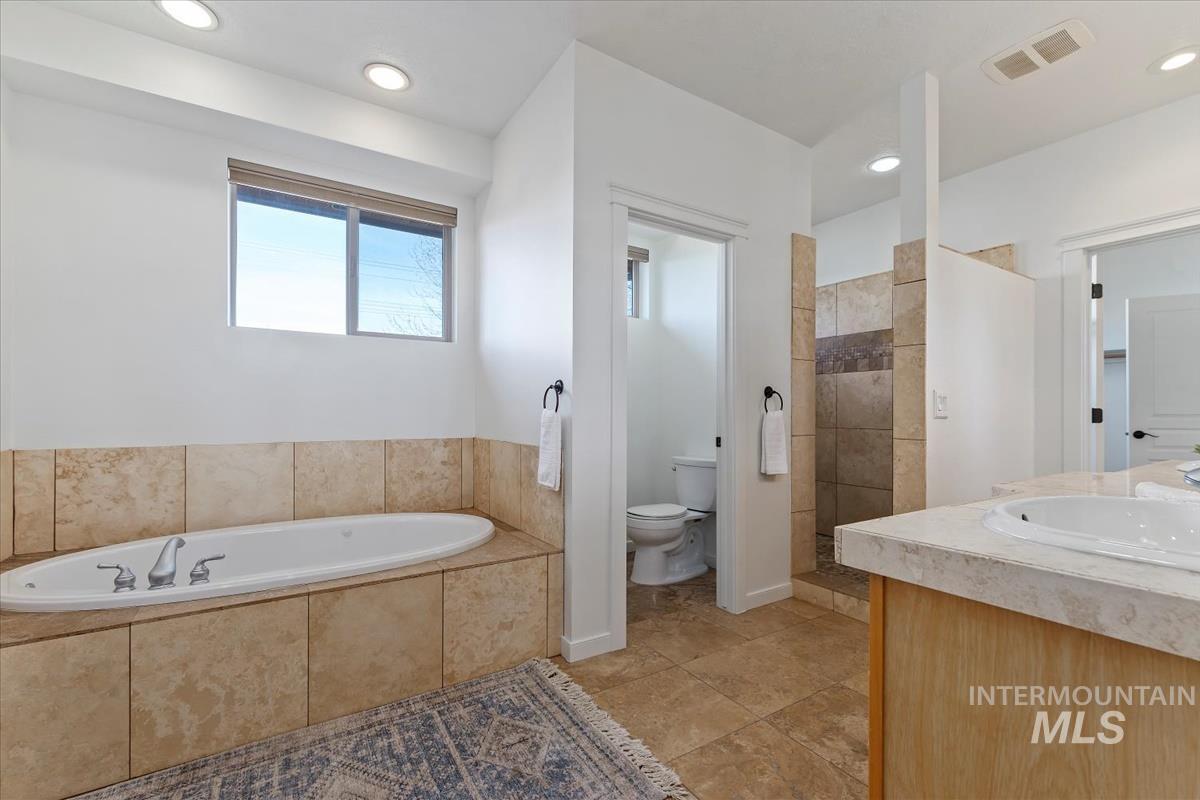 Bathroom with a garden tub, recessed lighting, vanity, a walk in shower, and tile patterned flooring
