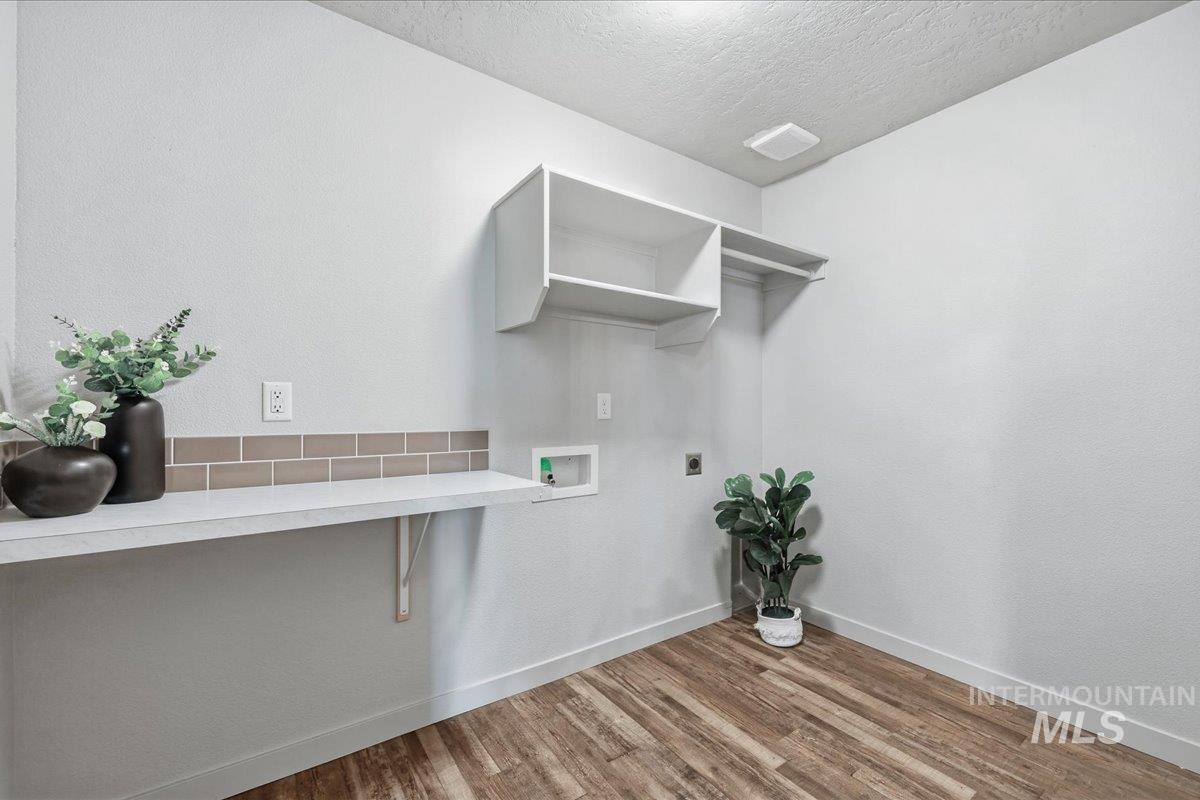 Washroom with washer hookup, light wood-style flooring, a textured ceiling, and electric dryer hookup