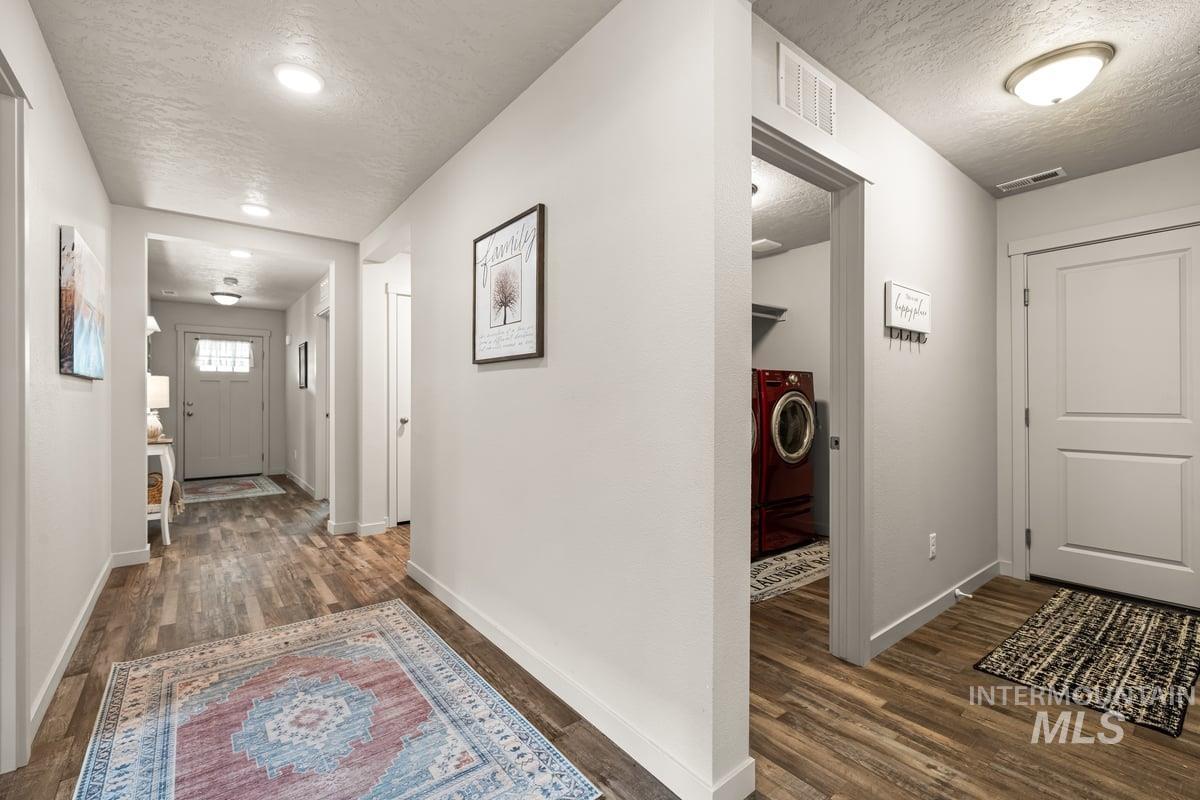 Hall featuring a textured ceiling, dark wood finished floors, and washer / dryer