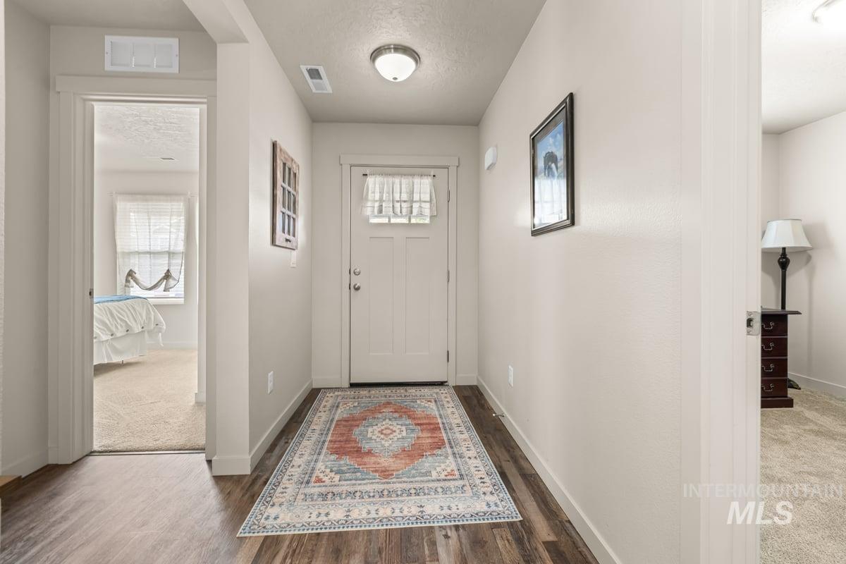 Carpeted foyer entrance featuring a textured ceiling, plenty of natural light, and wood finished floors