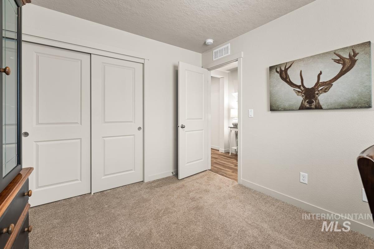 Bedroom with a textured ceiling, light colored carpet, and a closet