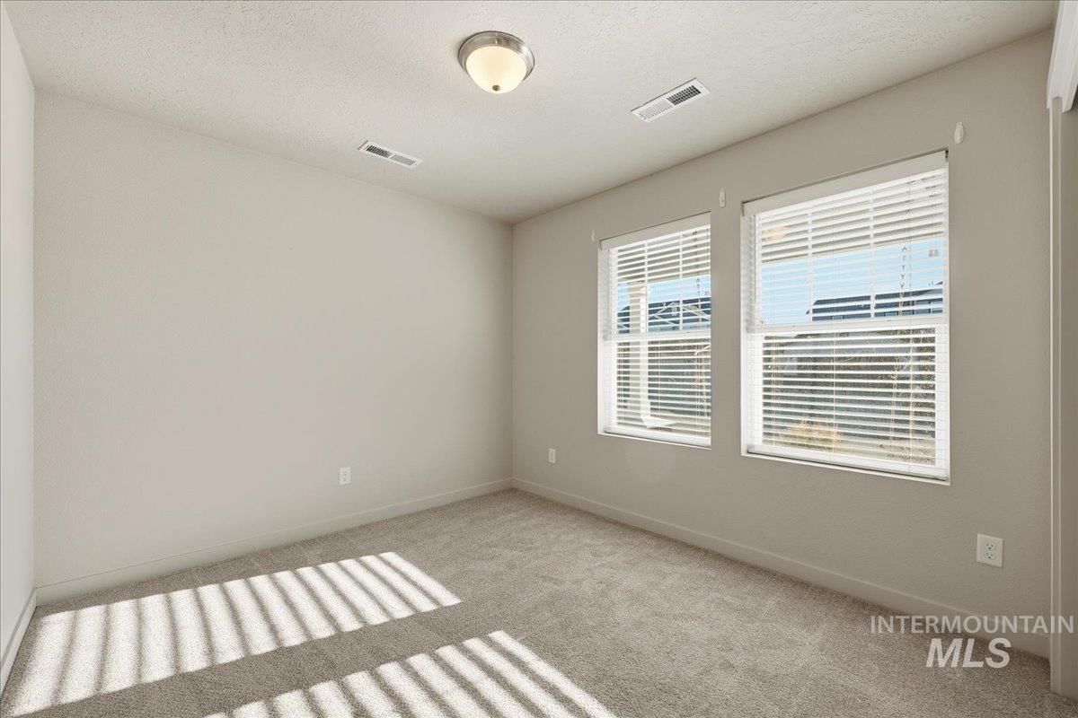 Empty room featuring a textured ceiling and light colored carpet