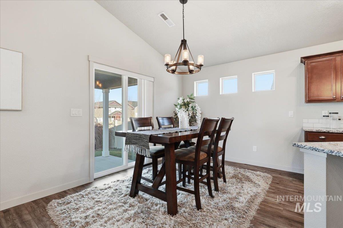 Dining space featuring lofted ceiling, dark wood-style floors, and a chandelier