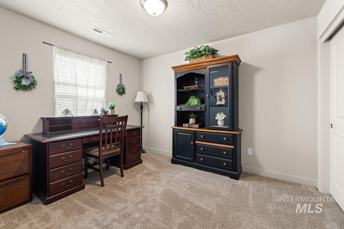 Office space with light carpet and a textured ceiling