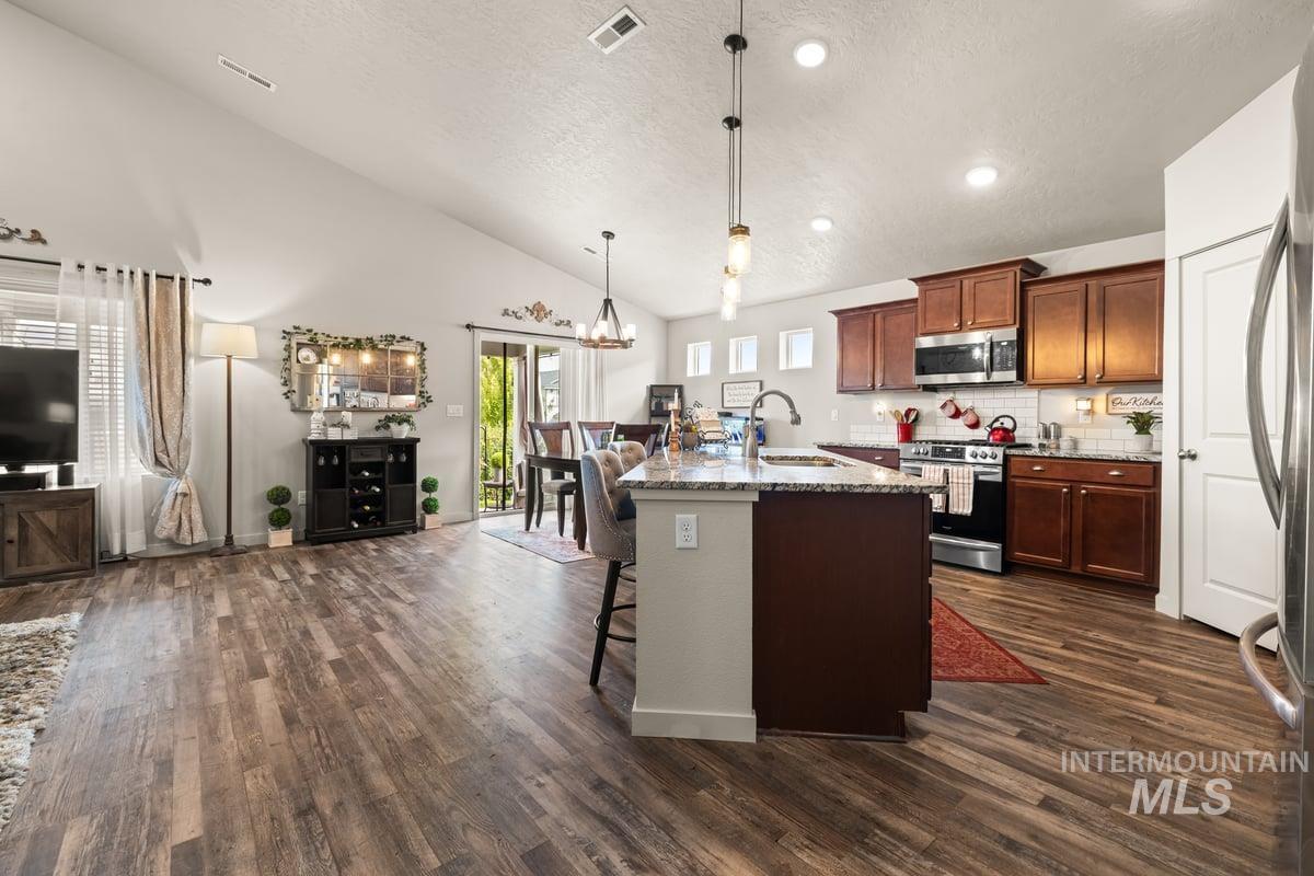 Kitchen featuring a breakfast bar, open floor plan, stainless steel appliances, backsplash, and light stone countertops