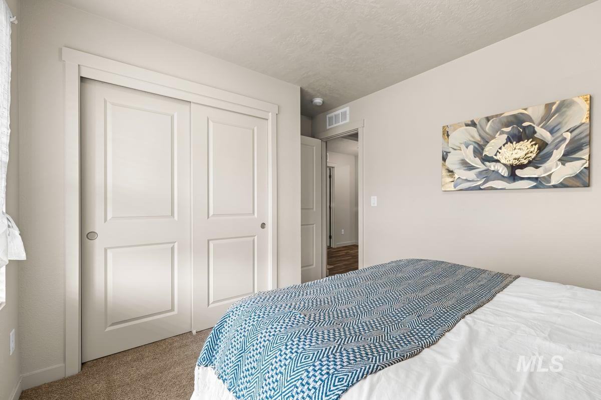 Carpeted bedroom with a textured ceiling and a closet
