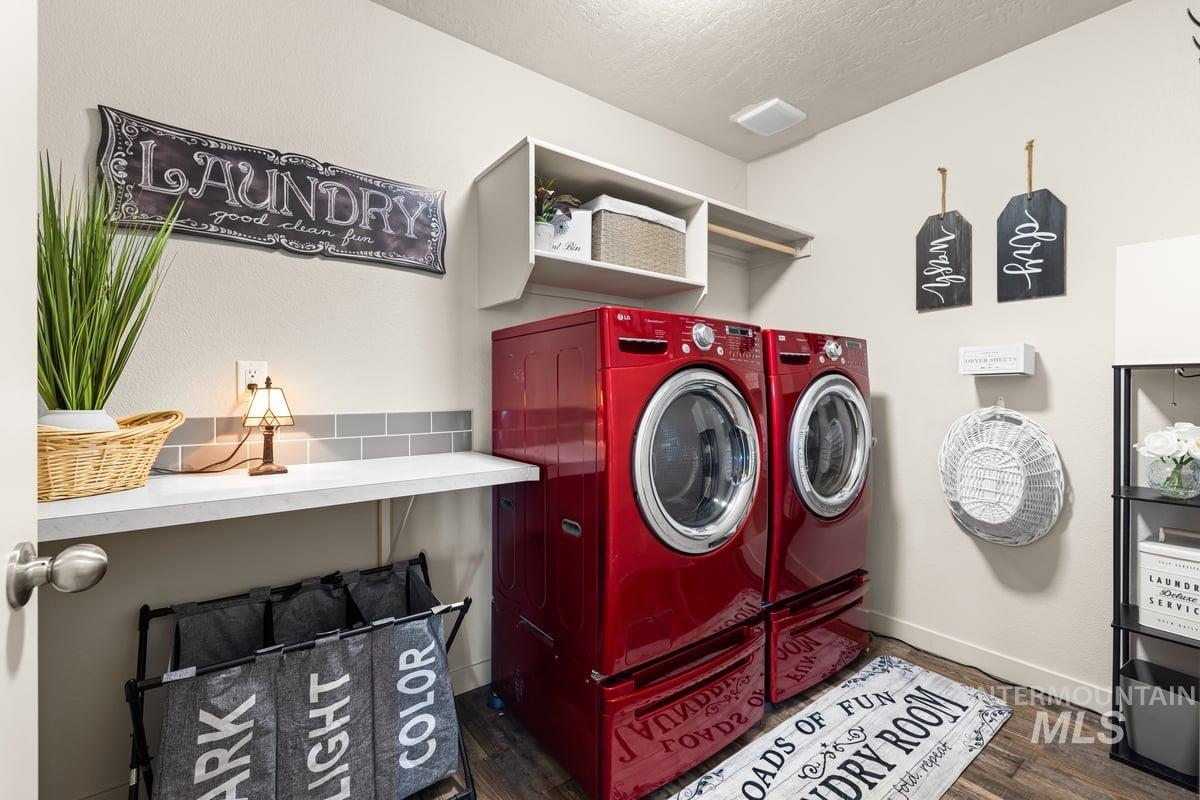 Laundry room with independent washer and dryer, dark wood-type flooring, and a textured ceiling
