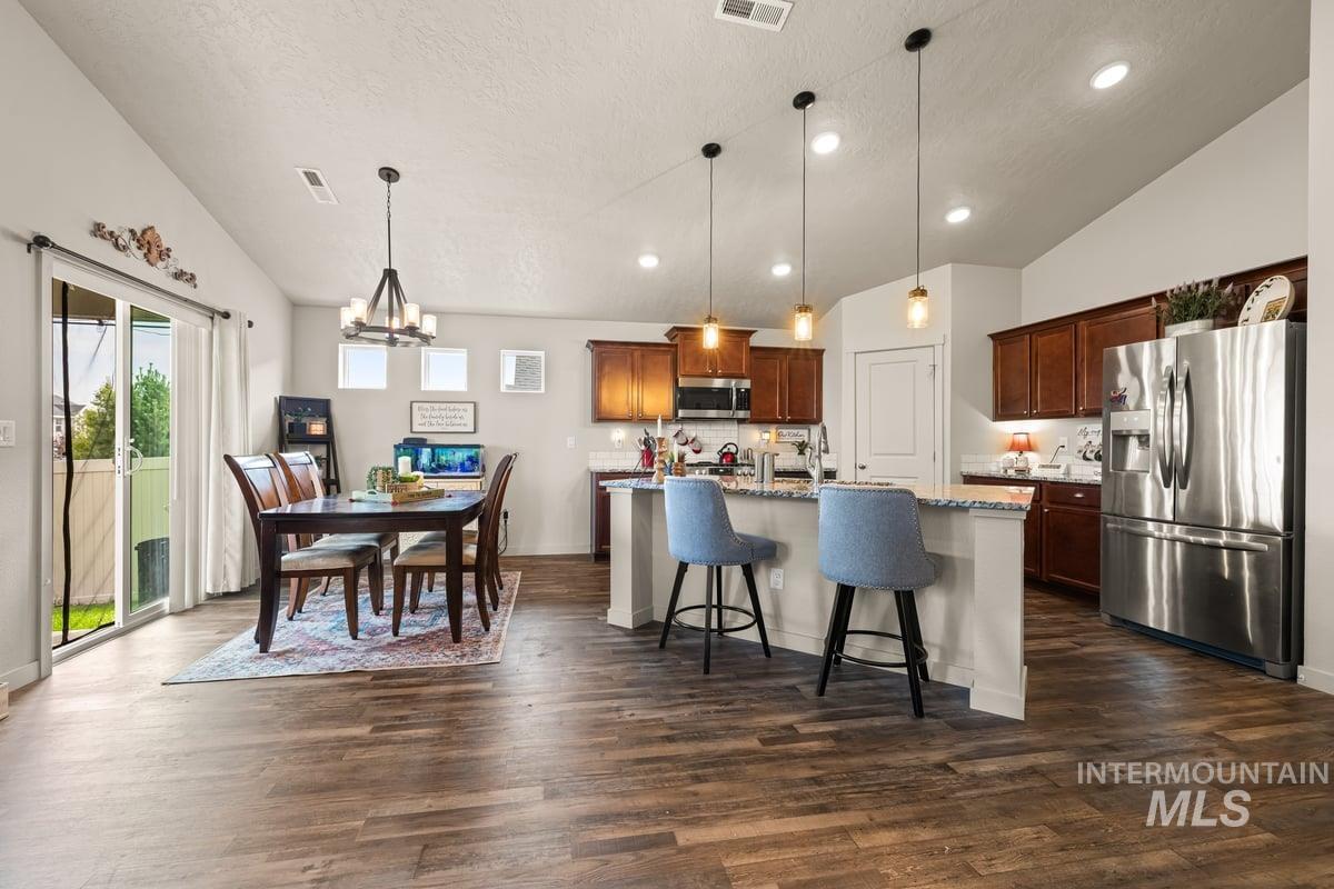Kitchen with vaulted ceiling, a breakfast bar area, appliances with stainless steel finishes, pendant lighting, and a chandelier