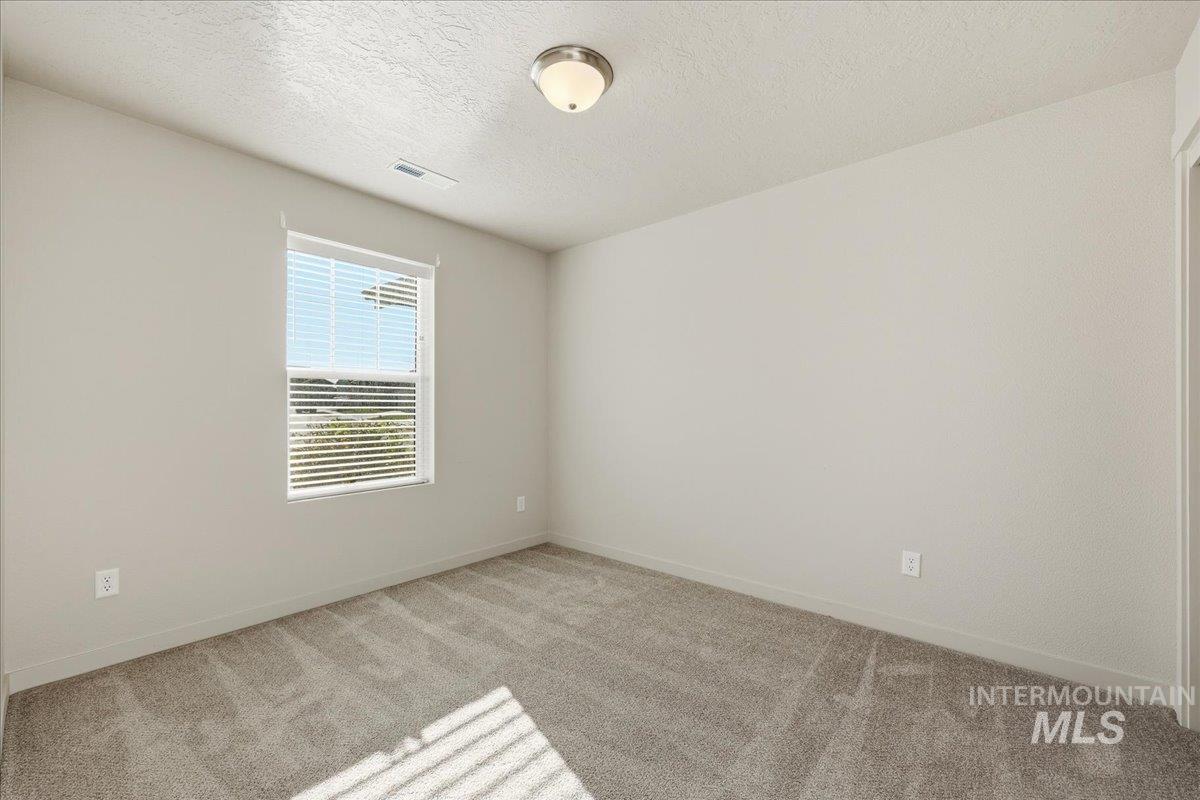 Spare room with a textured ceiling and light colored carpet