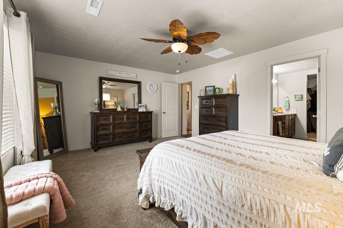 Carpeted bedroom featuring ceiling fan and a textured ceiling
