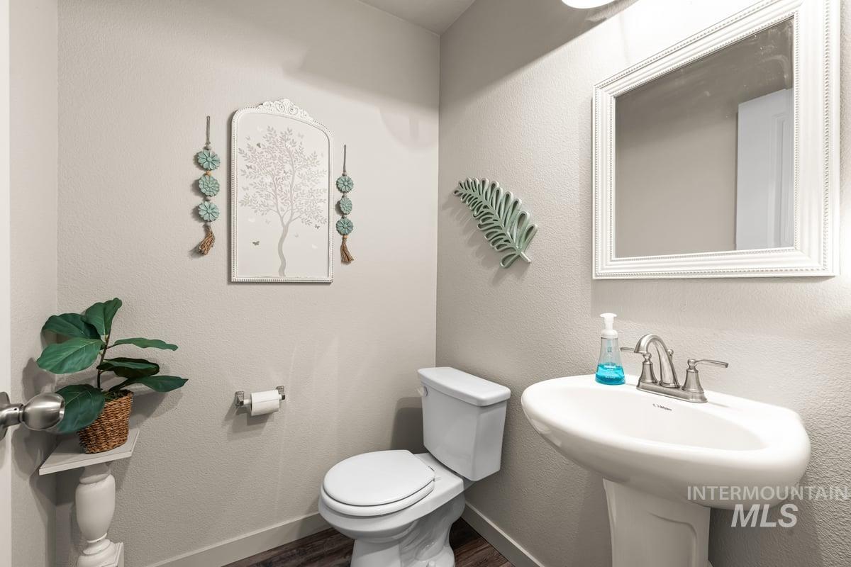Bathroom with a textured wall and dark wood-style floors