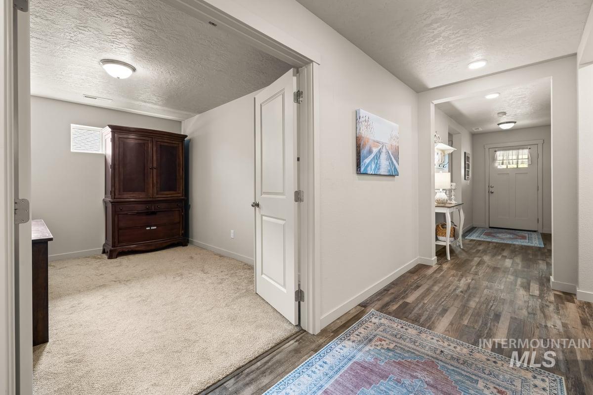 Corridor featuring a textured ceiling and dark wood-style floors