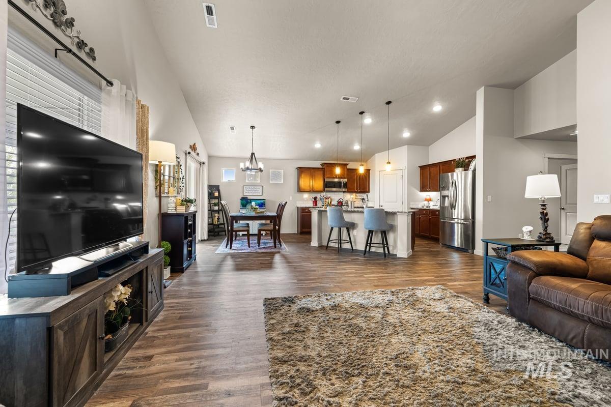 Living room featuring dark wood finished floors, a chandelier, and high vaulted ceiling