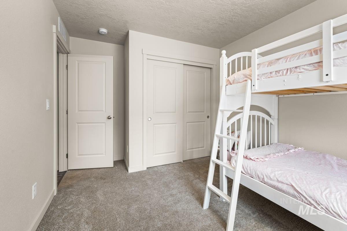 Carpeted bedroom featuring a textured ceiling and a closet