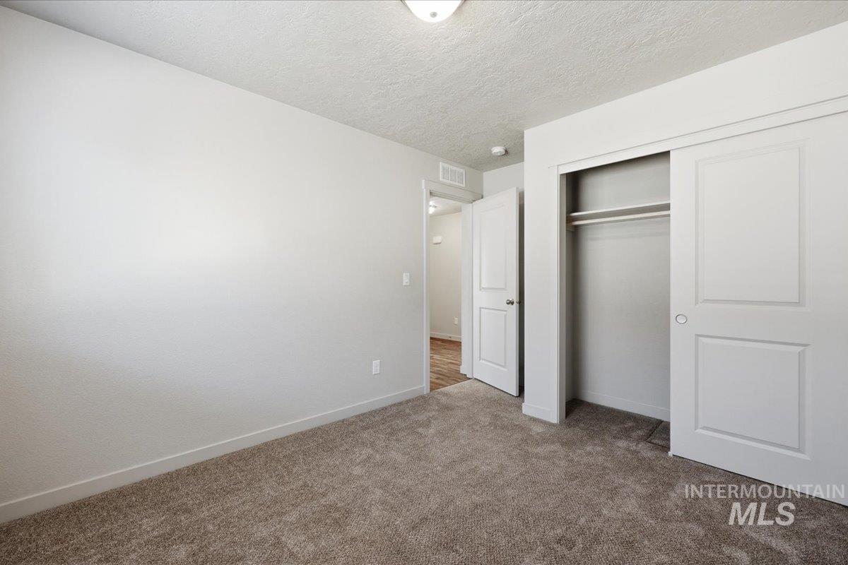 Unfurnished bedroom with a textured ceiling, a closet, and carpet