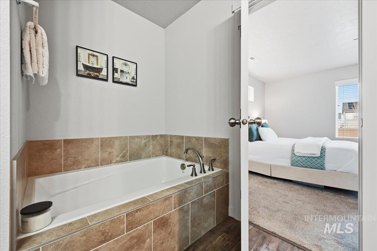 Bathroom with connected bathroom, a bath, wood finished floors, and carpet flooring