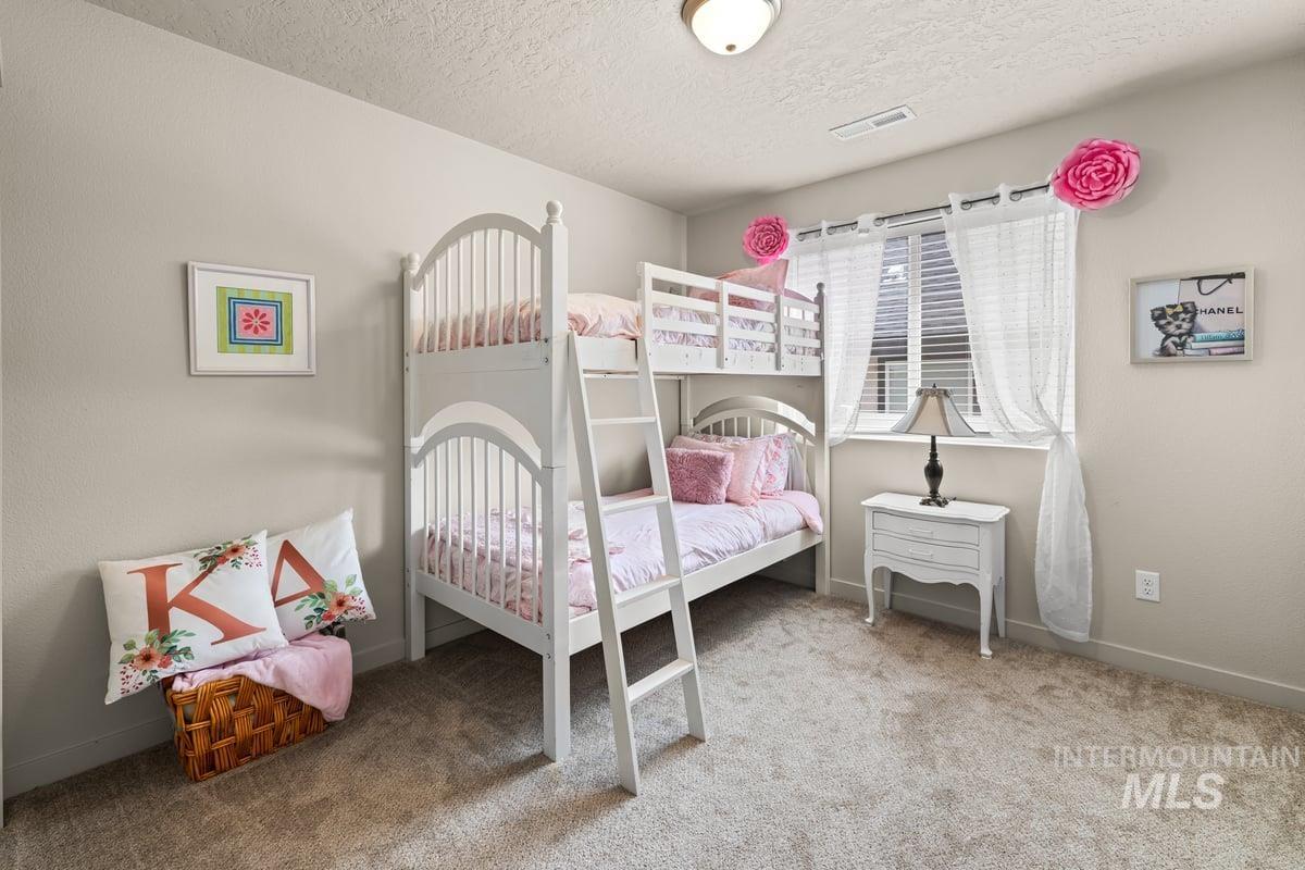 Bedroom featuring light colored carpet and a textured ceiling