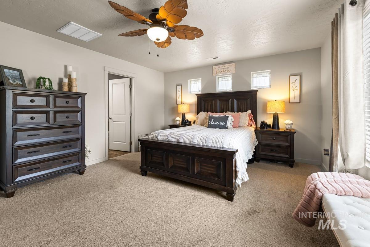 Bedroom with light carpet, a textured ceiling, and a ceiling fan