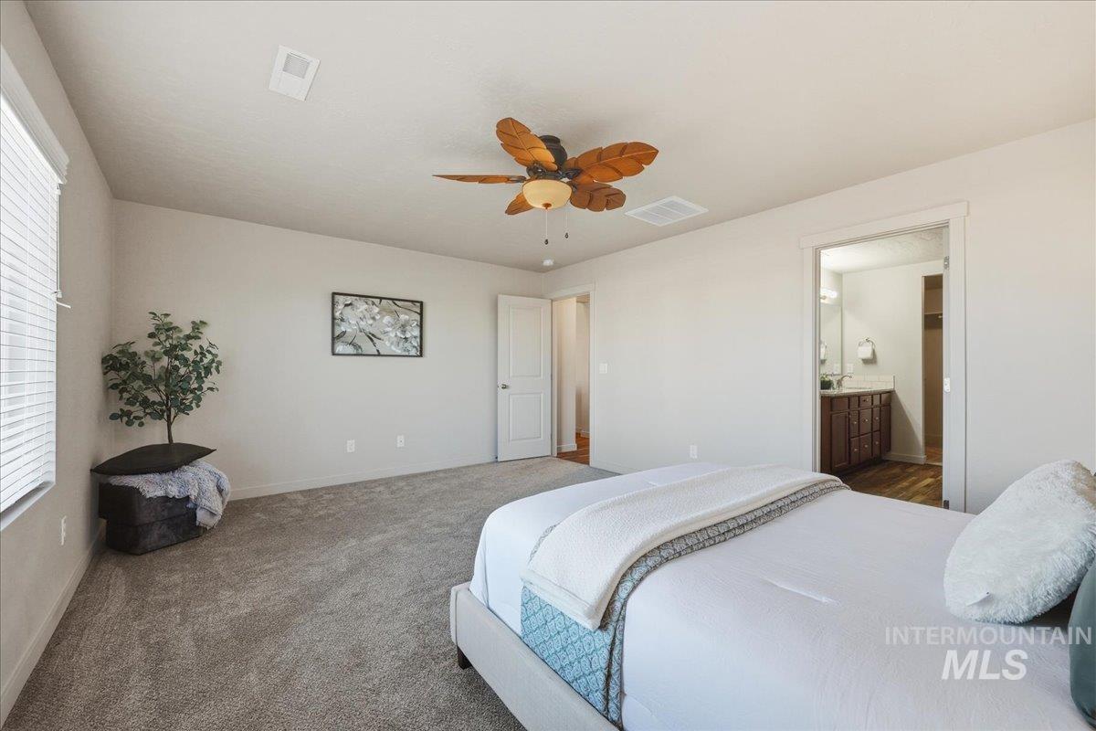 Bedroom featuring a ceiling fan, carpet, and ensuite bathroom