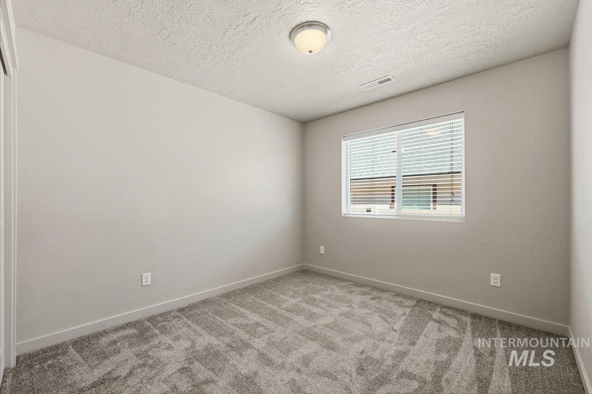 Empty room featuring a textured ceiling and light carpet