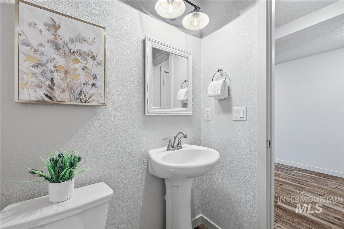 Half bath with a textured wall and wood finished floors