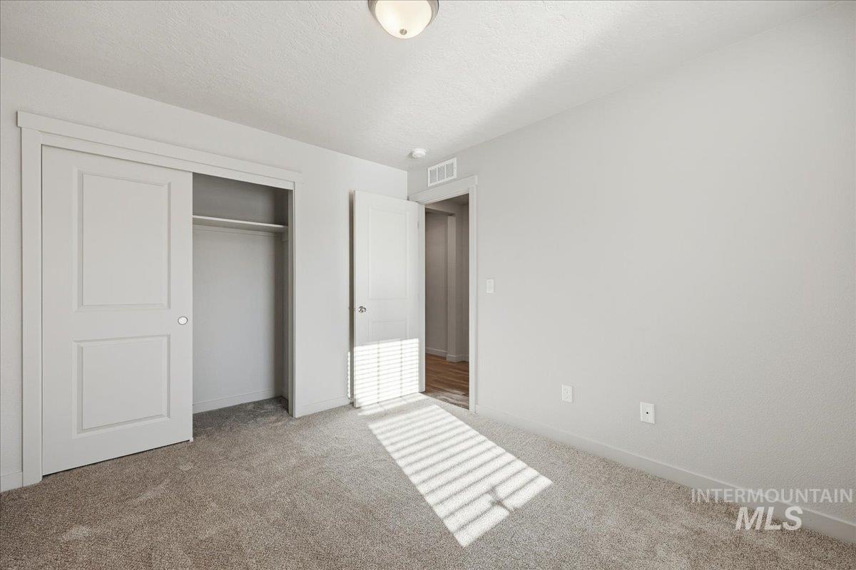 Unfurnished bedroom with a closet, a textured ceiling, and carpet flooring
