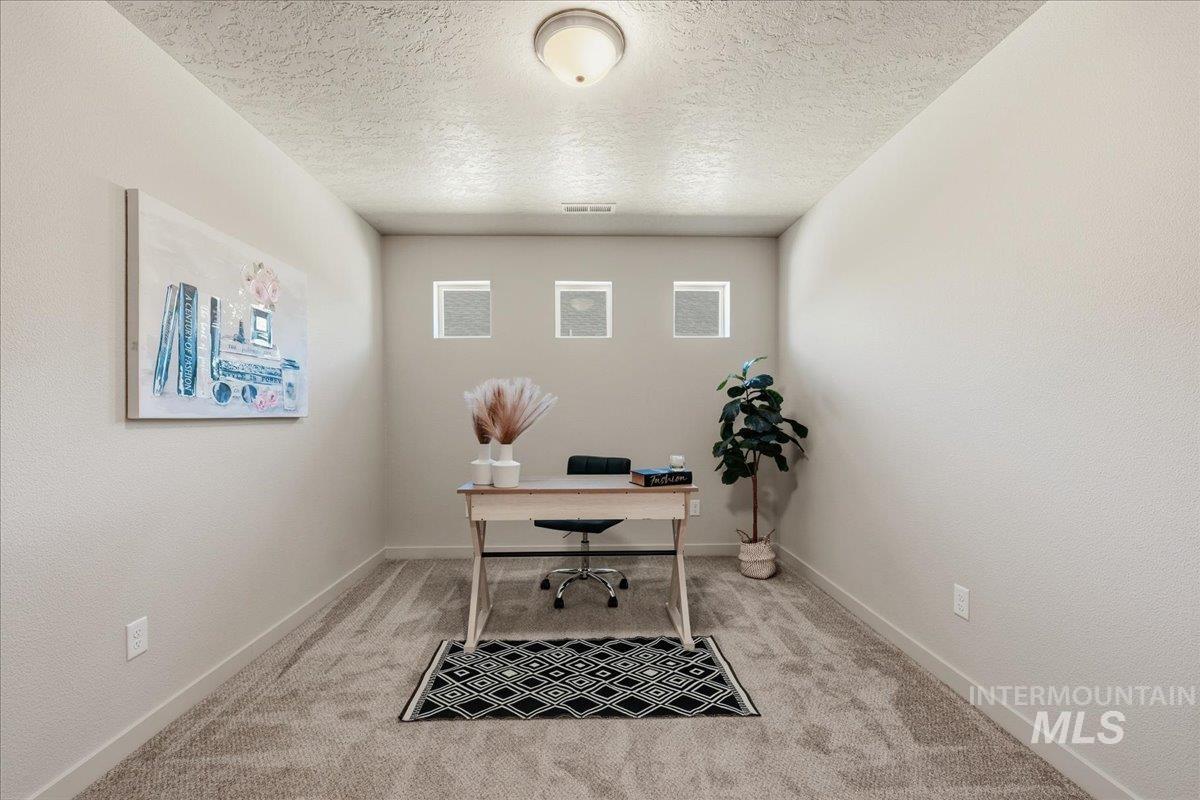 Office featuring light colored carpet and a textured ceiling