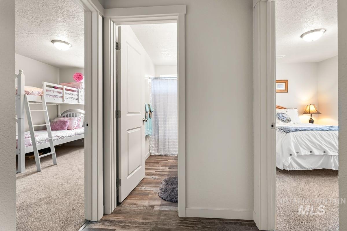 Hallway featuring a textured ceiling, dark colored carpet, and dark wood-type flooring