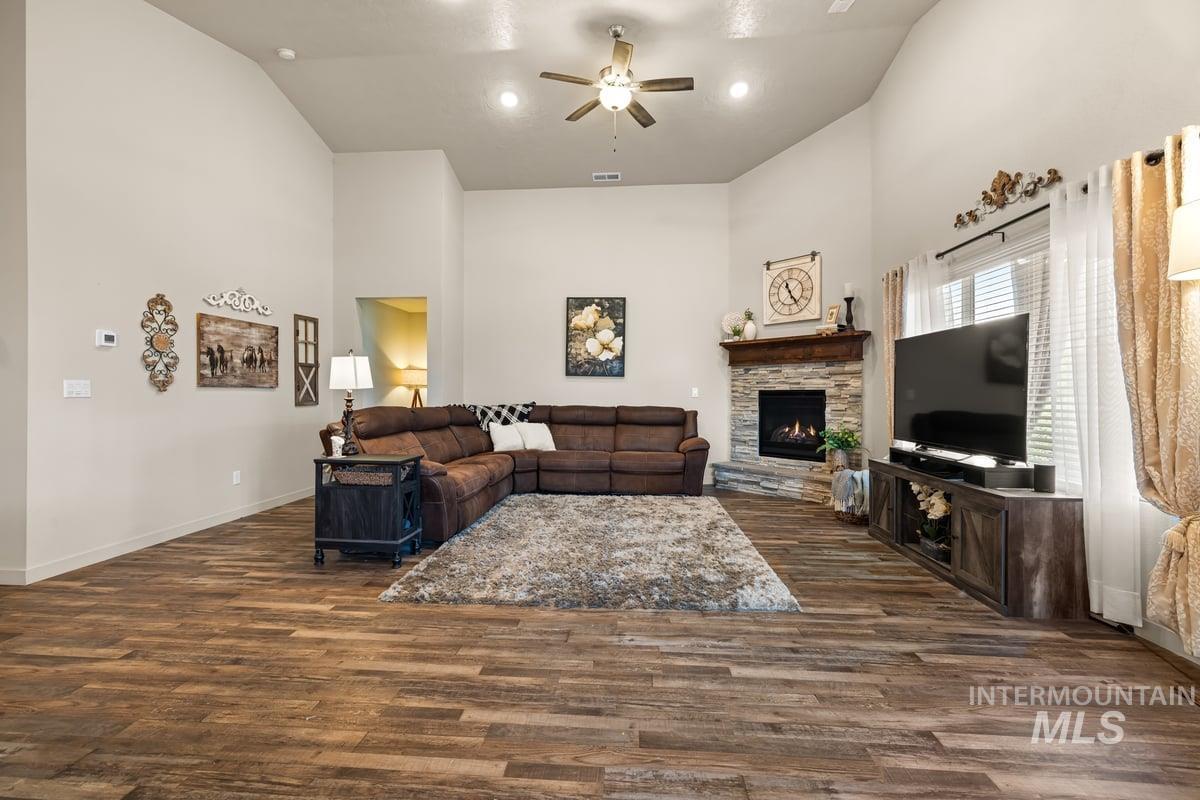 Living room featuring a fireplace, high vaulted ceiling, dark wood-style floors, ceiling fan, and recessed lighting