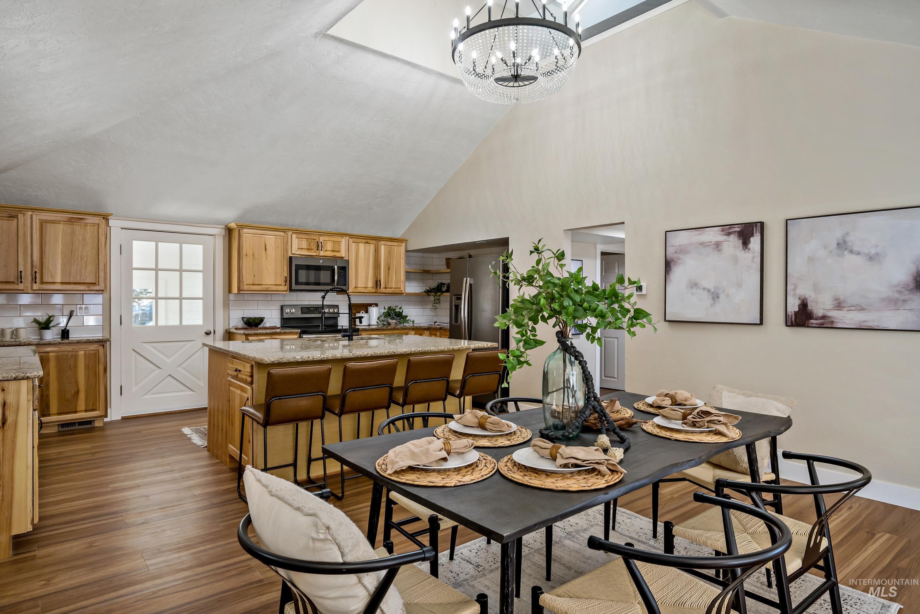 Dining space featuring high vaulted ceiling, dark wood-style flooring, and a chandelier