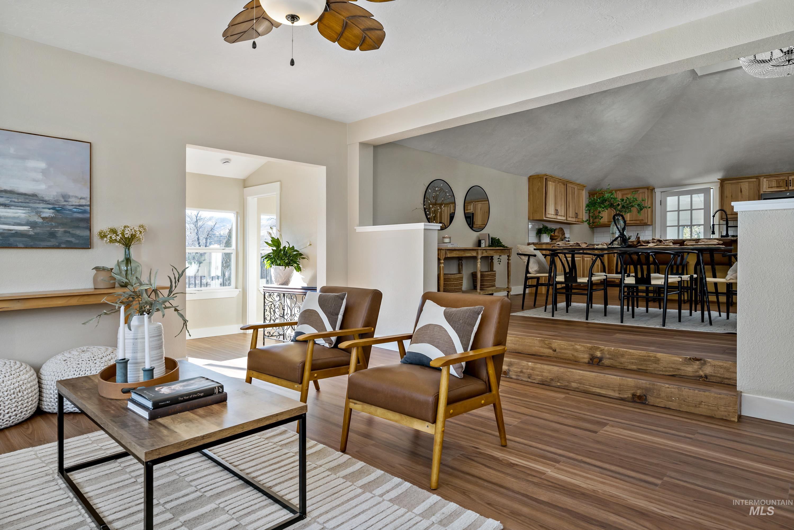 Living area featuring light wood-style flooring, a ceiling fan, and vaulted ceiling