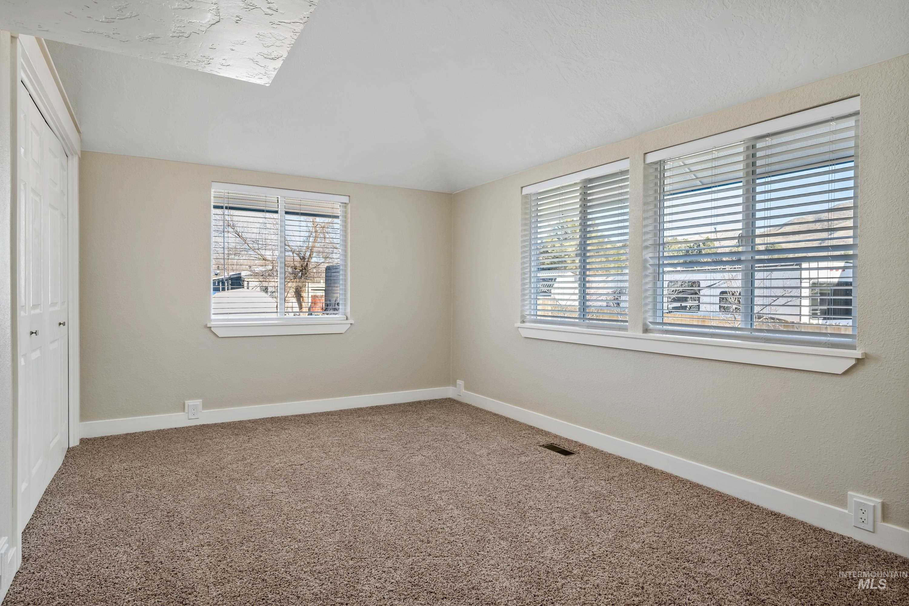 Unfurnished bedroom with carpet flooring, a closet, and vaulted ceiling