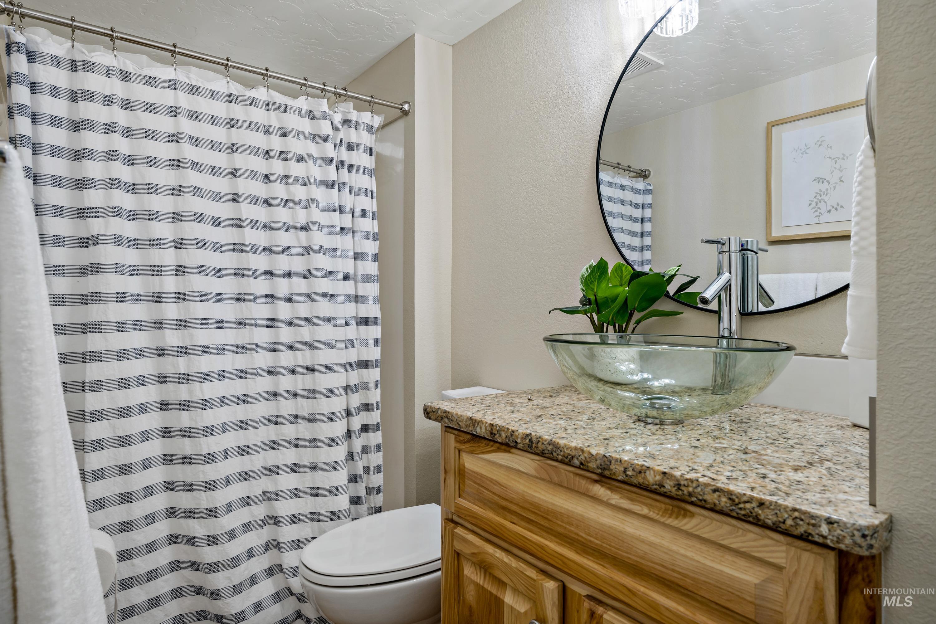Full bath featuring a textured wall, vanity, a textured ceiling, and a shower with shower curtain