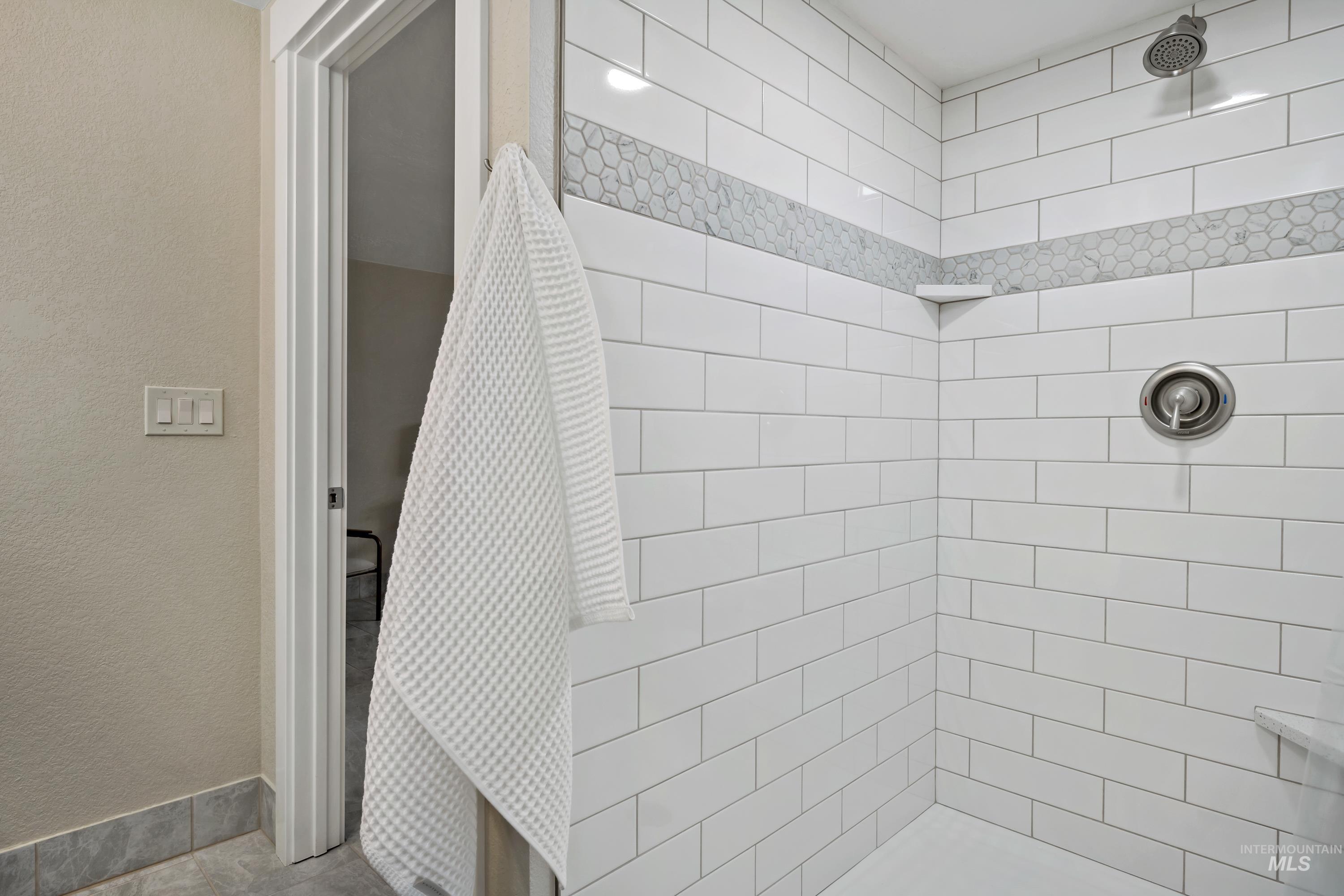 Bathroom with a tile shower and a textured wall