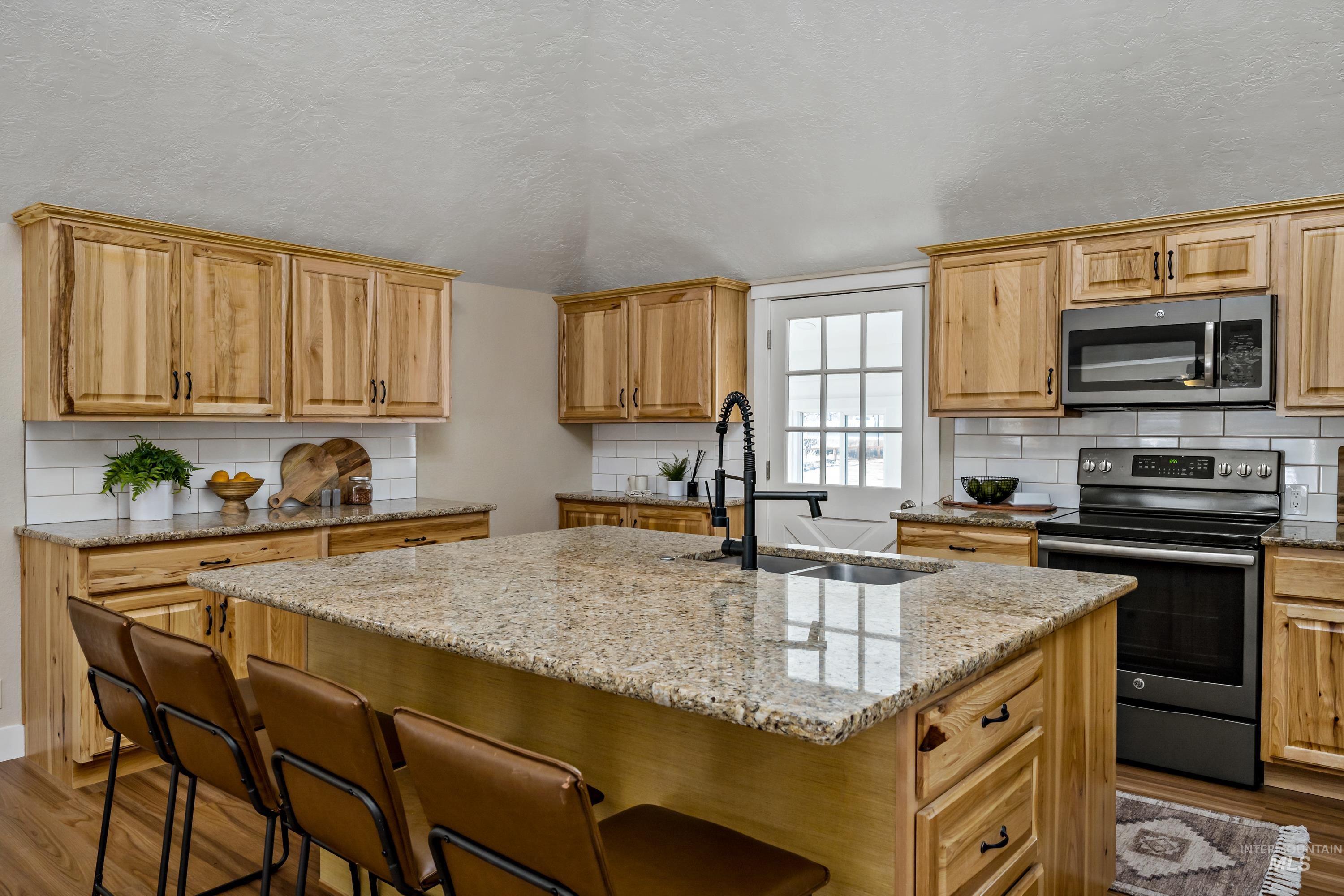 Kitchen featuring decorative backsplash, dark wood finished floors, and a textured ceiling