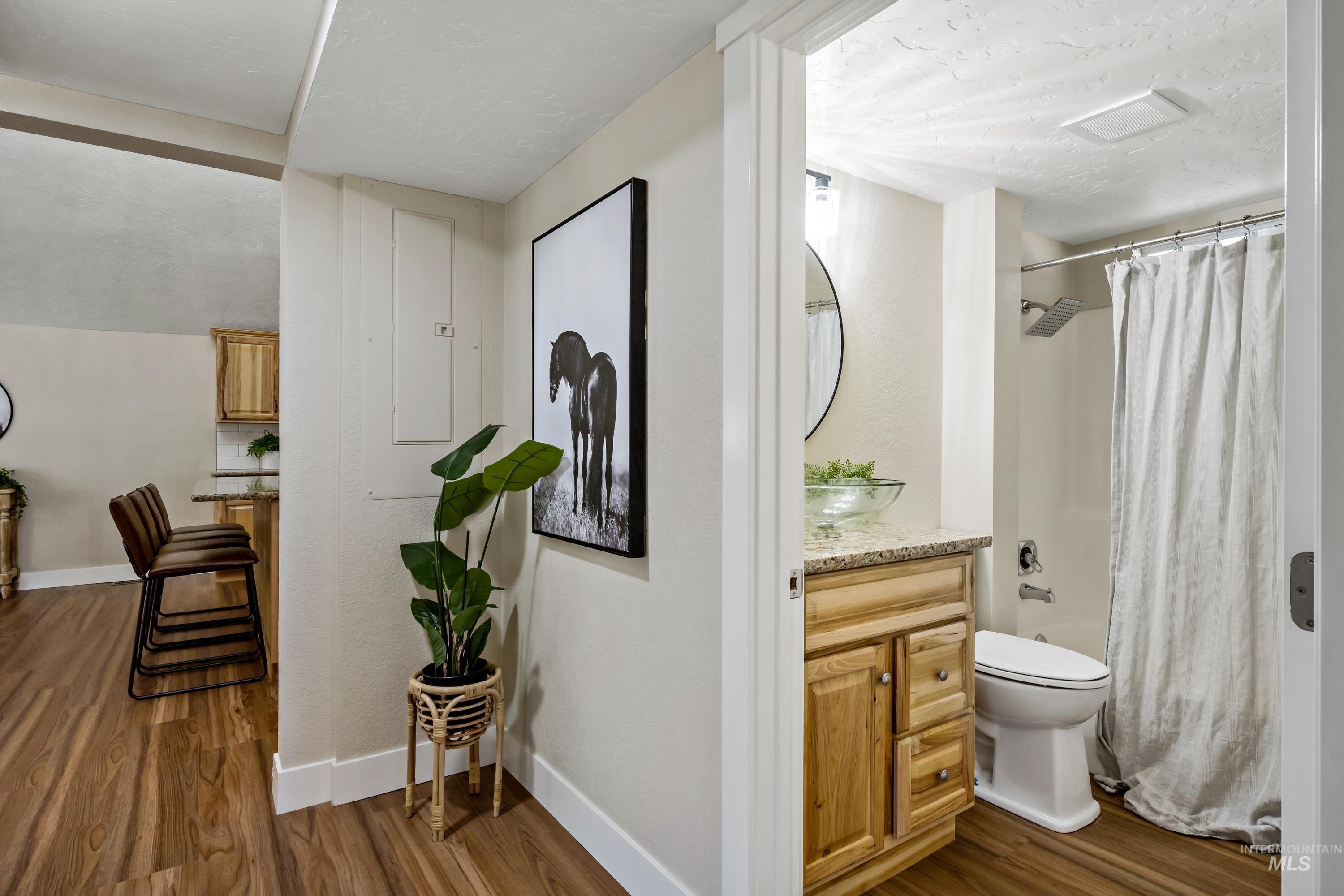 Bathroom featuring dark wood-type flooring, vanity, shower / tub combo, and a textured ceiling