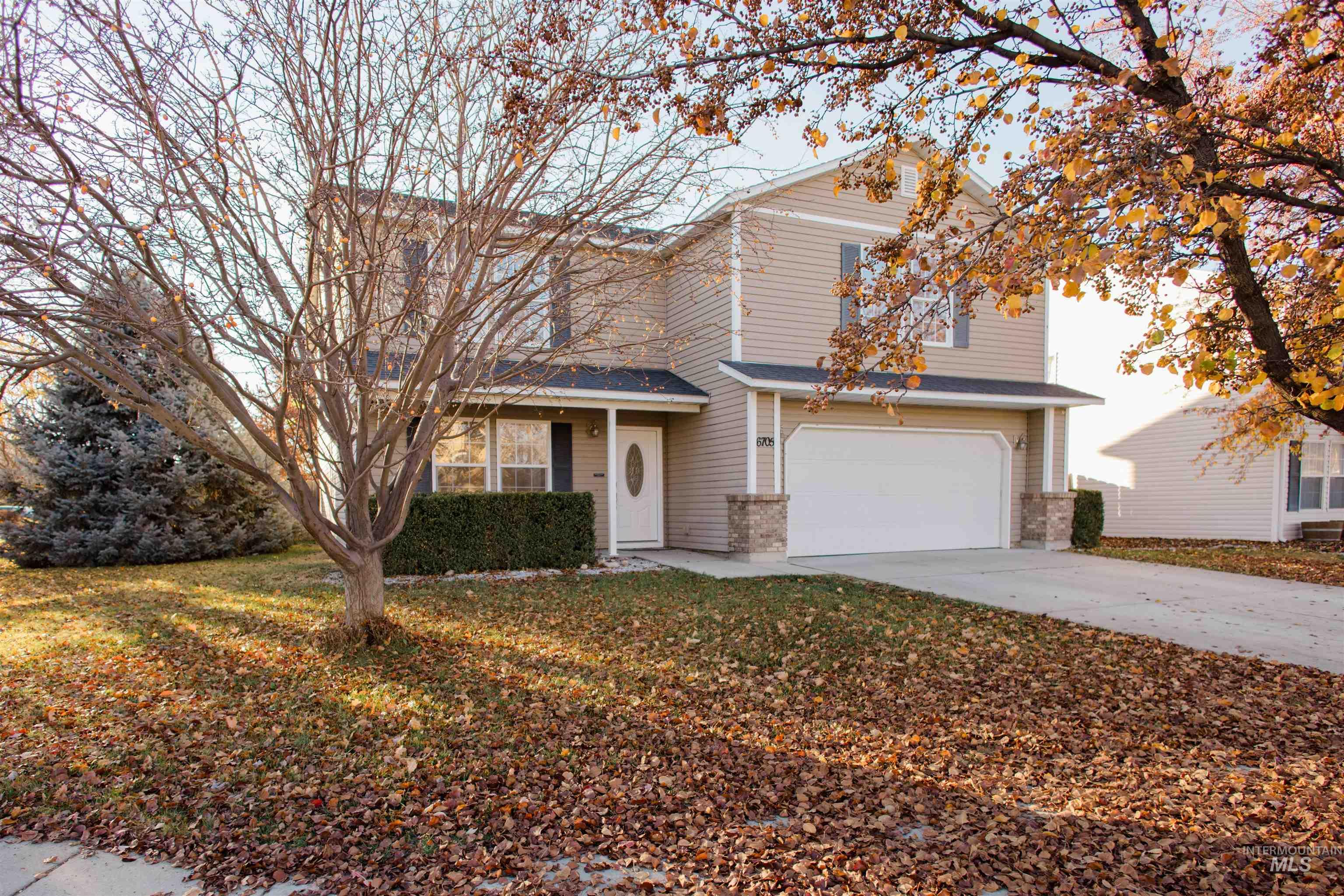 Traditional-style home with concrete driveway, a garage, brick siding, and a front lawn