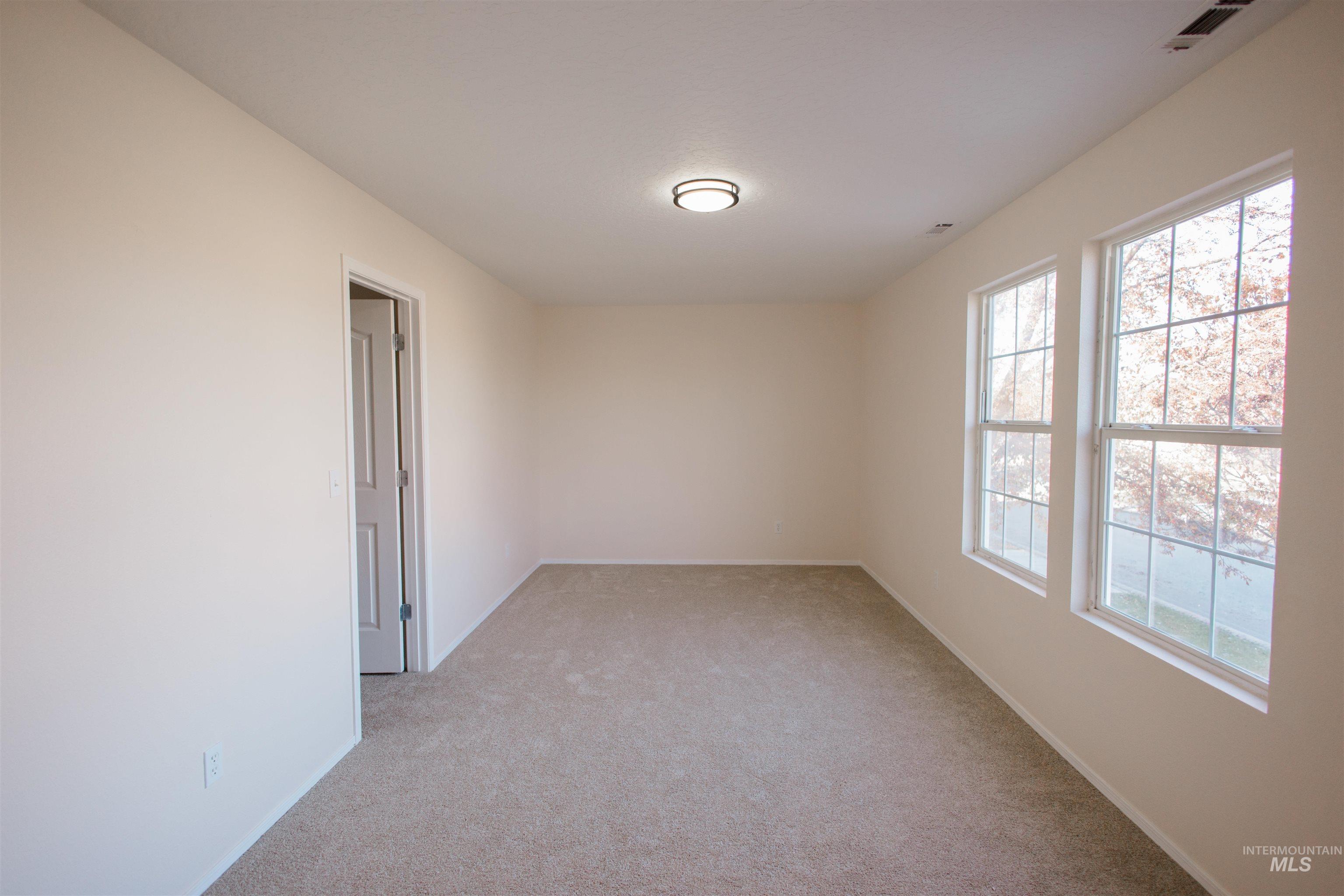Empty room with light colored carpet and baseboards
