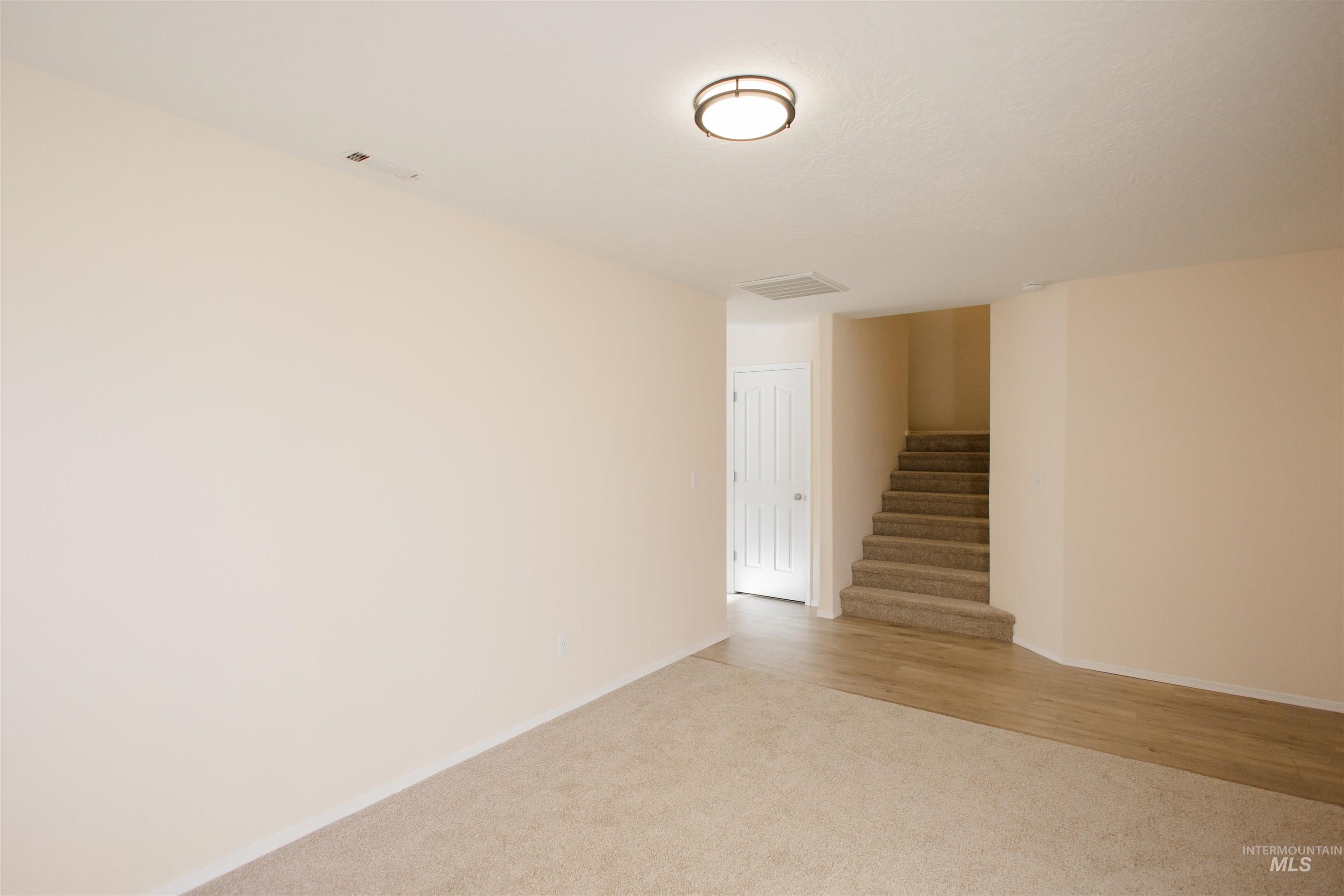 Empty room featuring light colored carpet and stairs