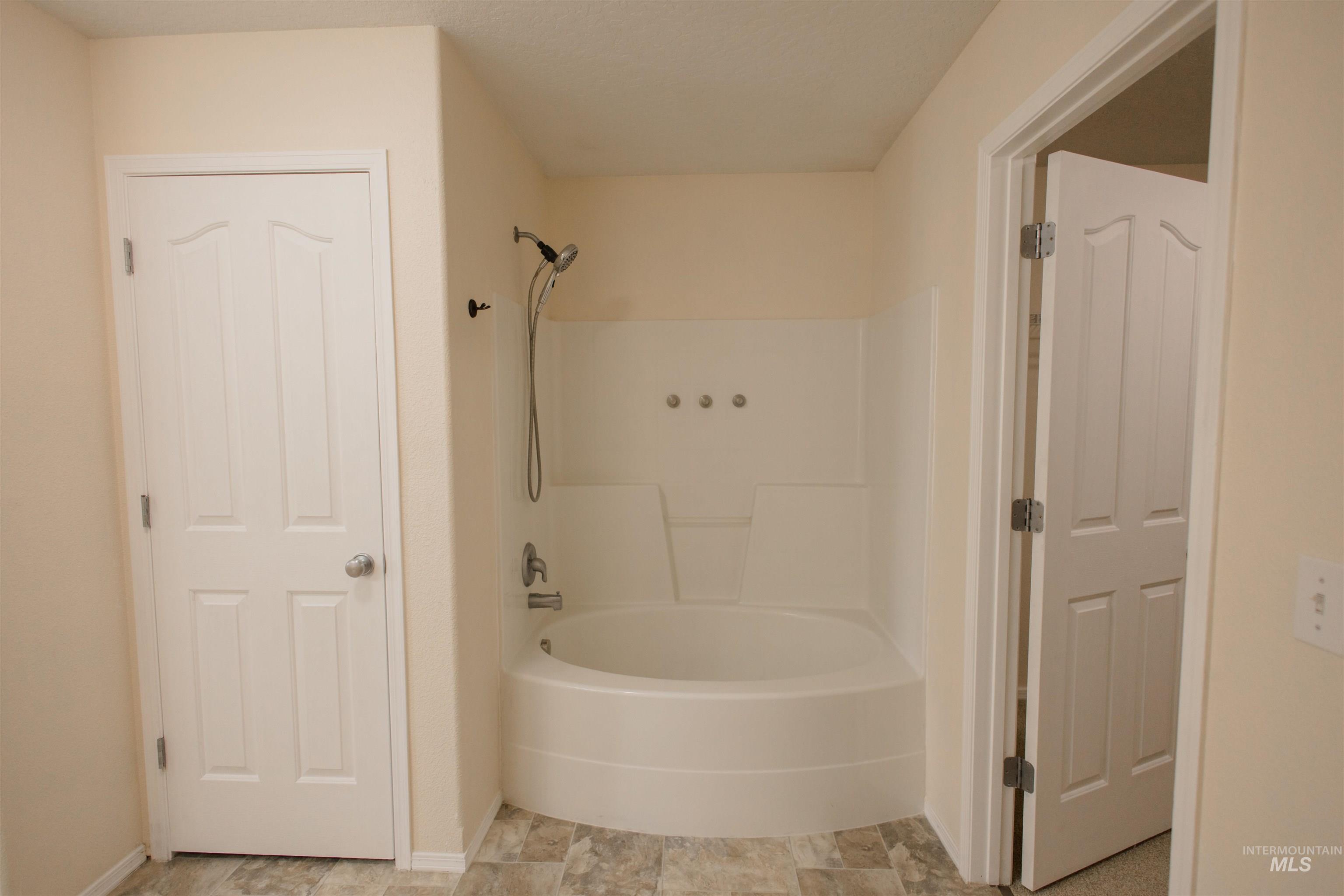 Full bathroom with shower / washtub combination and baseboards