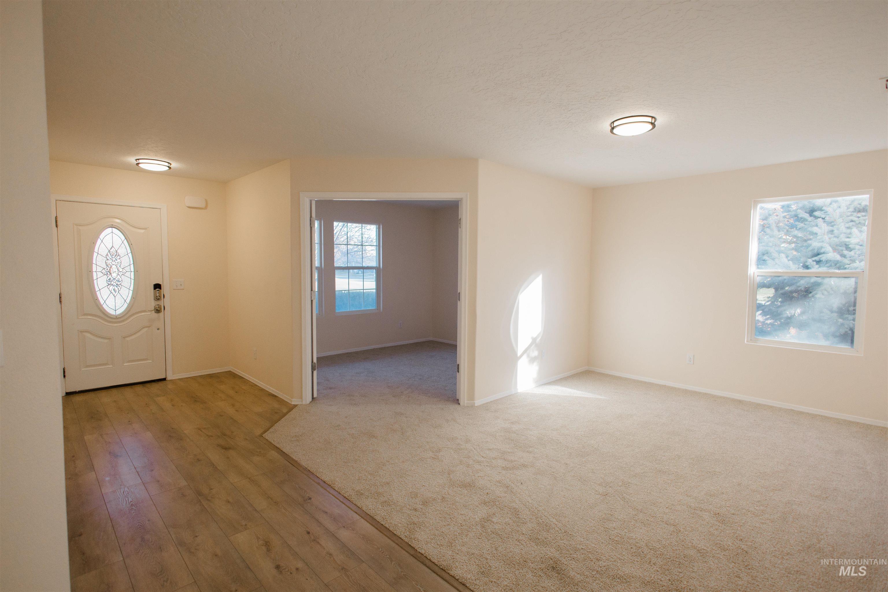 Foyer entrance with light wood-style flooring, plenty of natural light, and a textured ceiling