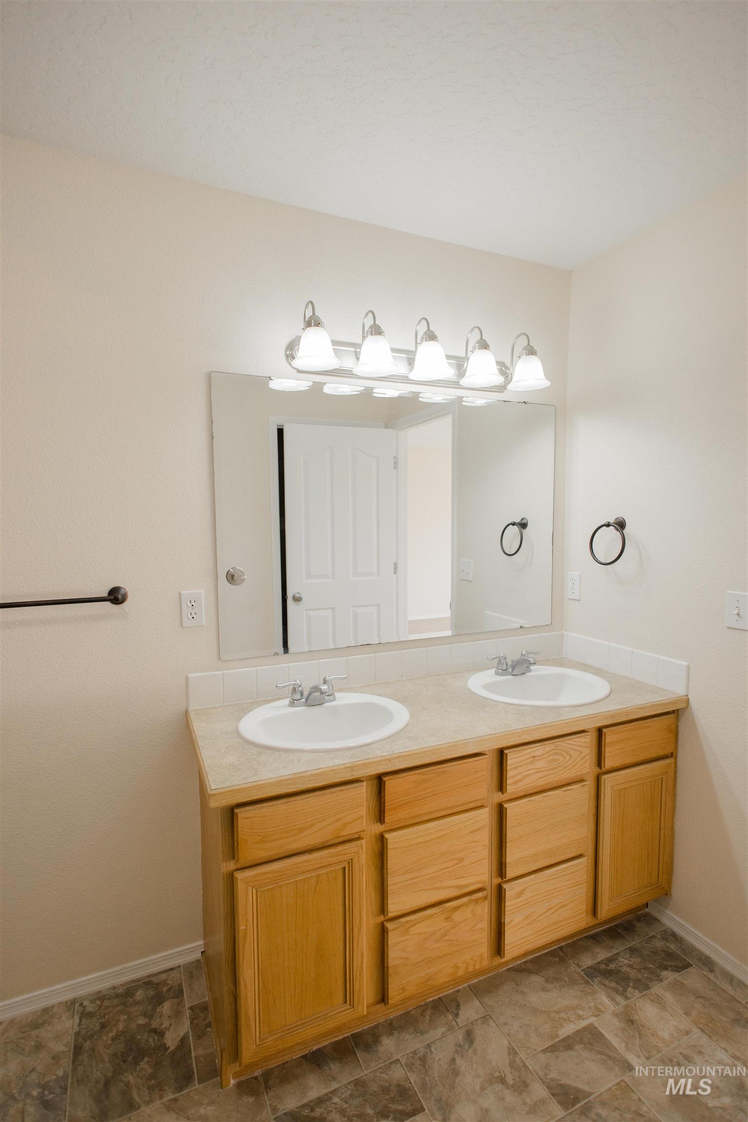 Full bath featuring double vanity and baseboards